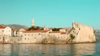 Mavi gökyüzü ile yaz manzarası ve kilise ile eski kasaba ve deniz dalgaları ile kule. Yaratıcı. Güzel doğa ve mimari.