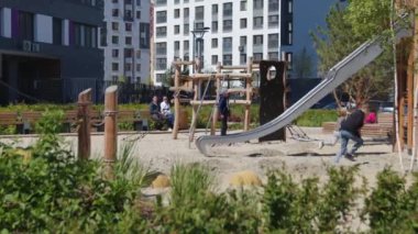 Bitkilerle dolu modern oyun parkı. Stok görüntüleri. Çocuklar modern oyun sahasında oynarlar. Yazın manzaralı ve oyun parklı bir yerleşim yeri.