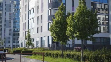 Konut kompleksinin güzel yeşil alanı. Stok görüntüleri. Konut binasının yakınında yeşil ağaçlar ve çalılar olan oyun parkı. Konut komplekslerinin modern manzarası ve mimarisi