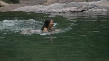 Yeşil gölde ya da nehirde yüzen bir kadın. Yaratıcı. Yaz tatili kavramı, soğuk yaz derelerinde yüzmek..