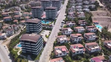 Yüzme havuzlu villaların ve otellerin havadan görünüşü. Şarjör. Binaların ve yeşil ağaçların üzerinde uçuyor güneşin altında..