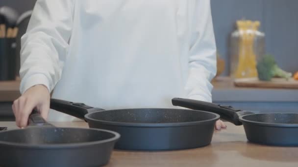 O cozinheiro recolhe panelas. Acção. Um homem com um casaco branco fica e coloca uma frigideira em outra e recolhe. — Vídeo de Stock