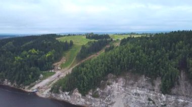  Güzel yeşil bir dağ. Clip. Drone 'un manzarası. Etrafında büyük köknar ağaçları ve nehir üzerinde duran bir patika olan büyük bir tepe..