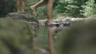 Yaz arazisi. Yaratıcı. Çıplak ayakla koşan ve çıplak ayakla çekilen çıplak ayaklı taşlarla şeffaf berrak su..