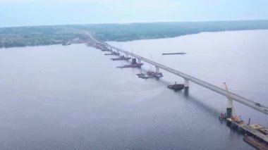 Büyük, uzun bir köprü. Clip. Helikopterden bak. Köydeki evlere giden büyük bir nehirden geçen büyük bir köprü ve yukarıdan beyaz gökyüzünü görebilirsin..