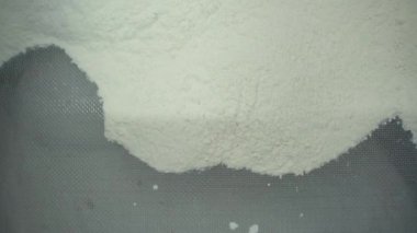 Beyaz un büyük bir elekten geçirilir. Şarjör. Elekten un düşmesi, yemek pişirme kavramı..