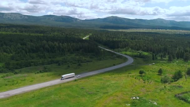 Luftaufnahme einer langen kurvenreichen Straße und grünen Wiese oder Feld auf bewölkten Himmel Hintergrund. Szene. Schöne Sommernatur. — Stockvideo