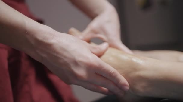 Крупним планом масаж ніг. Дія. Масажисти стискають руки клієнтів красивими ногами. Ніжний масаж ніг з оліями в спа-центрі — стокове відео