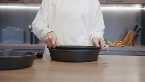 Närbild av kvinnliga händer visar nya stekpannor som för kök med ett löstagbart handtag. Börja. Begreppet husgeråd. — Stockvideo