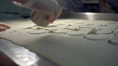 Eldiven takıp hamur çemberleri çizerek bir el yaklaş. Şarjör. Fabrikadaki hamur köftesi üretim süreci.