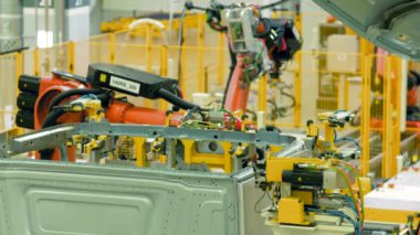 Fabrikada otomatik araba montajı. Sahne. Otomatik makineler metal yapıyı bir araya getiriyor. Modern üretim tesisinde robotik ekipman