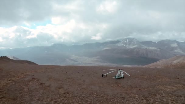 Vista superior del helicóptero de pie en la montaña. Clip. Helicóptero detenido en la montaña con vista al horizonte con nubes. Hermoso paisaje con montañas y rayos de sol en nubes nubladas — Vídeo de stock