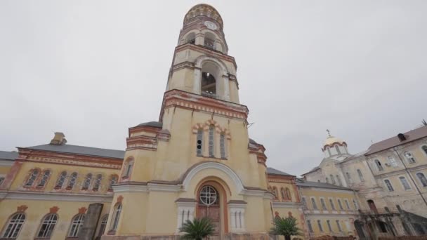 Bottom view of a church building with a tower. Action. Concept of architecture and religion, yellow facade building on a cloudy sky background. — Stock Video