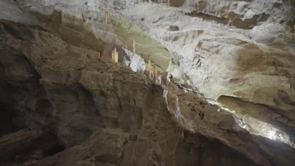 Podzemní jeskynní útvary stalaktitů a stalagmitů. Akce. Pohled do jeskyně na obřích kamenných zdech. — Stock video