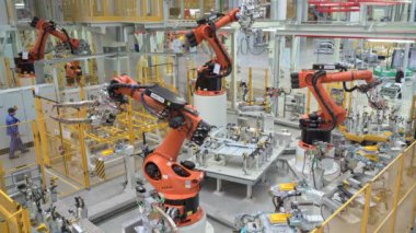 Rusya, Moskova - 7 Mayıs 2022: Robot ve işçilerle otomatikleştirilmiş fabrika. Sahne. Birçok robot makine modern fabrikada araba parçaları üretir. İşçilerin olduğu fabrikada modern robotik ekipman