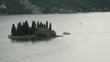 Karadağ, Perast - 29 Temmuz 2021: Ortaçağ kaleli adanın en üst manzarası. Yaratıcı. Körfezin ortasında ortaçağ mimarisi olan güzel bir ada manzarası. Aziz George Adası tarihi bir yerdir.