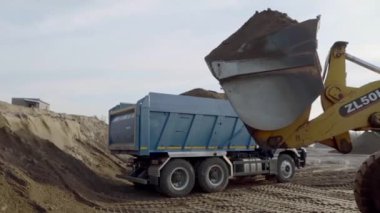 Kovası kumla dolu bir maden kamyonunun yan görüntüsü. Sahne. Ağır sanayi ve makine konsepti, taş ocağında endüstri geçmişi.