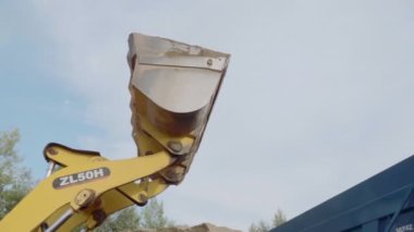 Kovası kumla dolu bir maden kamyonunun yan görüntüsü. Sahne. Ağır sanayi ve makine konsepti, taş ocağında endüstri geçmişi.