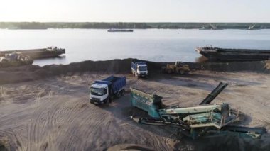 Kazıcı plajı temizliyor. Sahne. Plaj alanının en üst manzarası. Kazıcı ve çöp kamyonları yazın kıyı şeridini temizler. Sahilde inşaat işi.