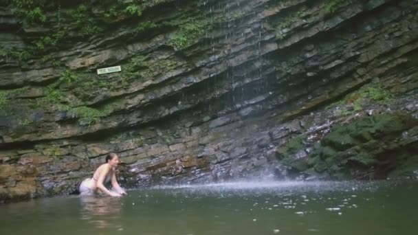 Dziewczyna nurkuje w płytkiej wodzie. KREATYWY. W pobliżu kamieni jest jezioro. Długowłosy mężczyzna kąpie się w stawie. Gruba dziewczyna nurkuje w stawie — Wideo stockowe