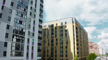 Yüksek binalar. Tock görüntüleri. Birçok aracın geçtiği yolun yanındaki büyük evler. Bulutsuz gökyüzünü görebilirsiniz. .