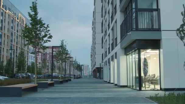 Byt bytový komplex a chodník pro pěší zdobené stromy a lavice v blízkosti budov. Záběry ze skladu. Nové město spací plochy. — Stock video