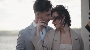 Güzel, genç bir gelin ve zarif bir damat rüzgarlı bir günde dışarıda dikiliyor. Başla. Kameranın önünde poz veren evli bir çift..