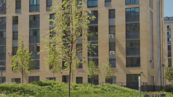 Un gran edificio de gran altura.Una casa de ladrillo amarillo brillante que se toma de arriba a abajo y junto a ella hay un patio y los árboles crecen. — Vídeos de Stock