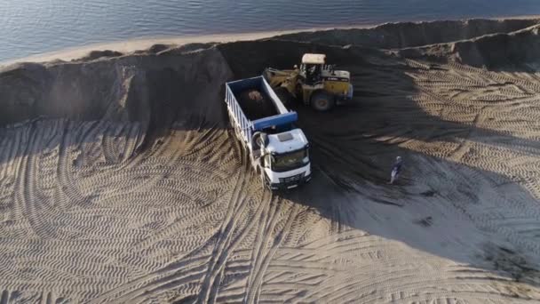 Estados Unidos, California - 20 de mayo de 2022: excavadora excavando y cargando arena en un camión volquete en la orilla del río. Escena. Maquinaria pesada que trabaja en cantera de arena. — Vídeo de stock