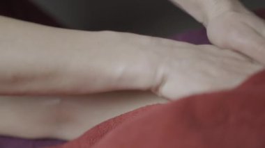 Spa tedavileri. Aksiyon. Havluların üzerinde yatan ve vücudunun farklı yerlerine krem sürülen genç bir kız. Yüksek kalite 4k görüntü