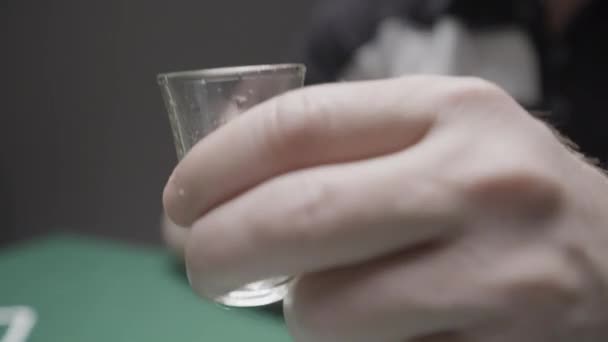 ウォッカを飲んでいる男のクローズアップ アクション ポーカーをしながらガラスを飲む 黒いメガネのロシアのバンドイットウォッカを飲み カードをプレイ — ストック動画