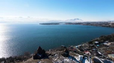 Ahşap eski binalarla dolu bir tepenin havadan görünüşü. Görüntü. İlkbaharda tepeler karla kaplanırken ve üzerinde açık gökyüzü olan sakin mavi deniz