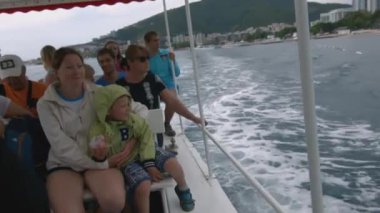 Yunanistan, Atina - 5 Haziran 2022: Turistler açık deniz gezisi için tekneyle açılıyorlar. Yaratıcı. Teknedeki turistler kıyıda esintiyle yelken açıyorlar. Turistler kıyı boyunca deniz turuna çıkar.. 
