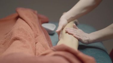 Masaj salonunda rahatla. Hareket. Üzerinde bir kızın masaj yaptırdığı mavi bir tezgah ve yağlı beyaz bir fincan tabağı görünür. Yüksek kalite 4k görüntü