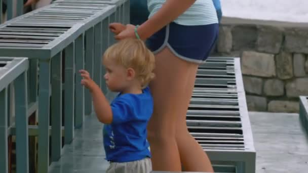 一个小男孩和他的年轻母亲爬上楼梯在街上的侧视图 城市露天剧场 — 图库视频影像