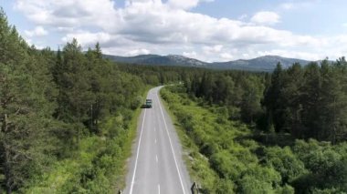 Ormandaki otobanda geçen arabanın en üst görüntüsü. Sahne. Güneşli bir günde ormanın olduğu güzel bir kır yolu manzarası. Şehir dışına seyahat..