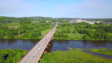 Nehrin yukarısında giden arabaların ve yeşil doğanın olduğu bir köprünün havadan görüntüsü. Şarjör. Ulaşım kavramı, yaz güneşli bir günde kırsal bölgede köprü.