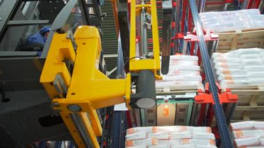 Rusya Moskova - 24 Şubat 2022: Forklift yükleyicisiyle karton kutuları taşıyan üniformalı depo işçisi. Yaratıcı. Forklift paleti büyük modern depoda kutularla dolu.