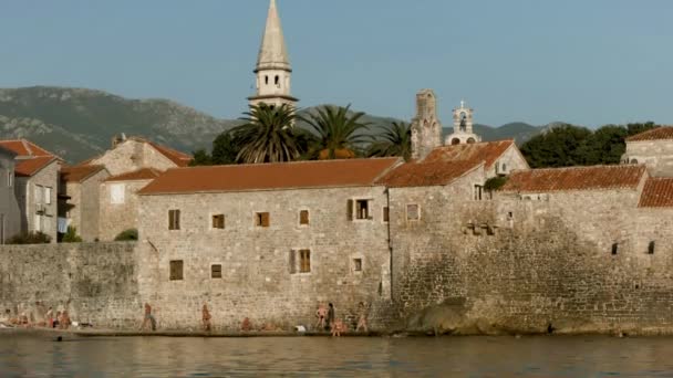 古老的城堡建在蓝天和高山背景的湖畔 旧石楼和行人 — 图库视频影像