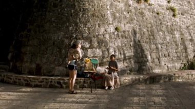 Türkiye, İstanbul - 7 Mayıs 2022: Anne ve oğlu antik taş bina yakınlarında yürüyorlar. Yaratıcı. Eski güzel kale ve aile yakınlarda geziyor.