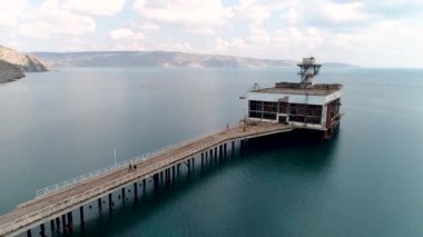 Eski paslı iskele ve mavi turkuaz suyun havadan görünüşü. Vuruldu. Terk edilmiş beton iskele ve deniz suyu.