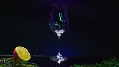 Bar tezgahında duran şeffaf bir bardağa yeşil kokteyl koymaya yakın. Borsa klipsi. Yeşil yapraklar ve portakalla süslenmiş bar tezgahı.
