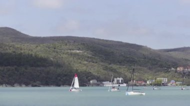 Turkuaz göl ve yeşil dağlarla nefes kesici bir manzara. Başla. Gök mavisi suda küçük yelkenli tekneler, seyahat konsepti.