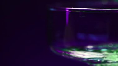 Gece kulübünde bir bardağa yeşil alkol kokteyli doldurmaya yakın. Borsa klipsi. Alkolizm ve kötü alışkanlıklar kavramı