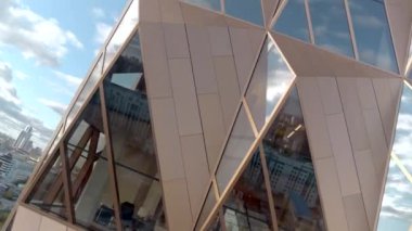 Kompleks geometrik şekilli, aynalı pencereli modern binanın etrafında uçuyor. Stok görüntüleri. Alışılmadık mimarisi, gökdeleni, büyük şehrin iş bölgesinde ofis bloğu olan bir yapı.