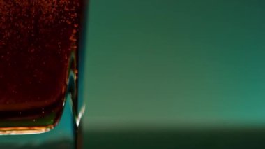 Bir bardağın içindeki kırmızı meşrubatı, rengini değiştiren bir duvara yaklaştır. Borsa klipsi. Bir bardak sodanın içinde hava kabarcıkları