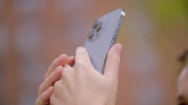 Güzel genç bir kadın video çekiyor. Başla. Uzun saçlı güzel bir kadın iPhone 13 'te harika aksesuarları olan videolar çekiyor. Yüksek kalite 4k görüntü