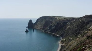 Manzaranın güzel bir kuş bakışı görüntüsü. Başla. Mavi okyanusun, dağların ve yeşil ağaçların üzerinde durduğu bir manzara ve kıyıya yakın yüzen küçük yelkenleri görebilirsiniz. Yüksek kalite 4k