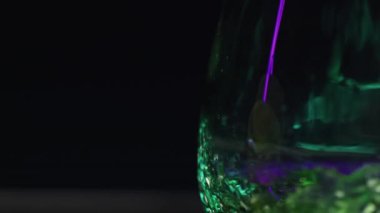 Barmen konsepti. Borsa klipsi. İçmek için doldurulan büyük bardakta parlak yeşil yanan içecekler. Yüksek kalite 4k görüntü