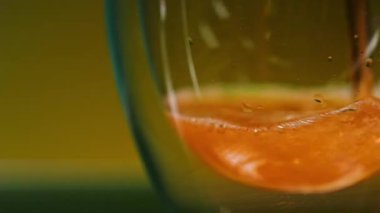 Bardağa dökülen taze portakal suyunun yakın çekim görüntüsü. Borsa klipsi. Bardakta taze, sağlıklı bir içeceğin yavaş hareketi.